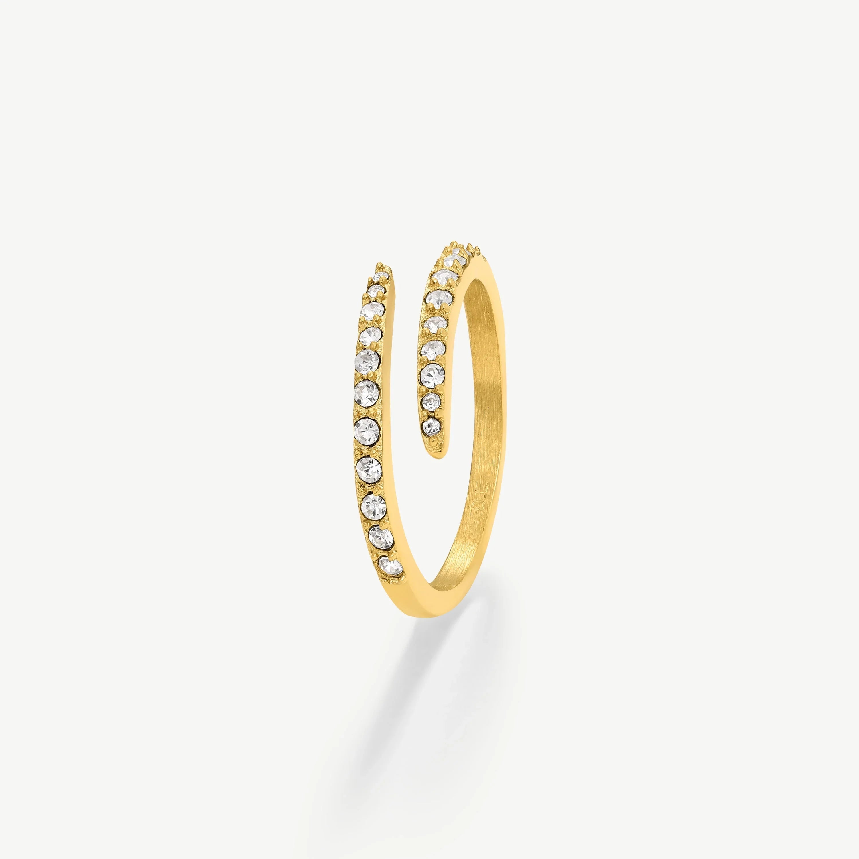 Gold spiral ring adorned with clear sparkling gemstones on a white background