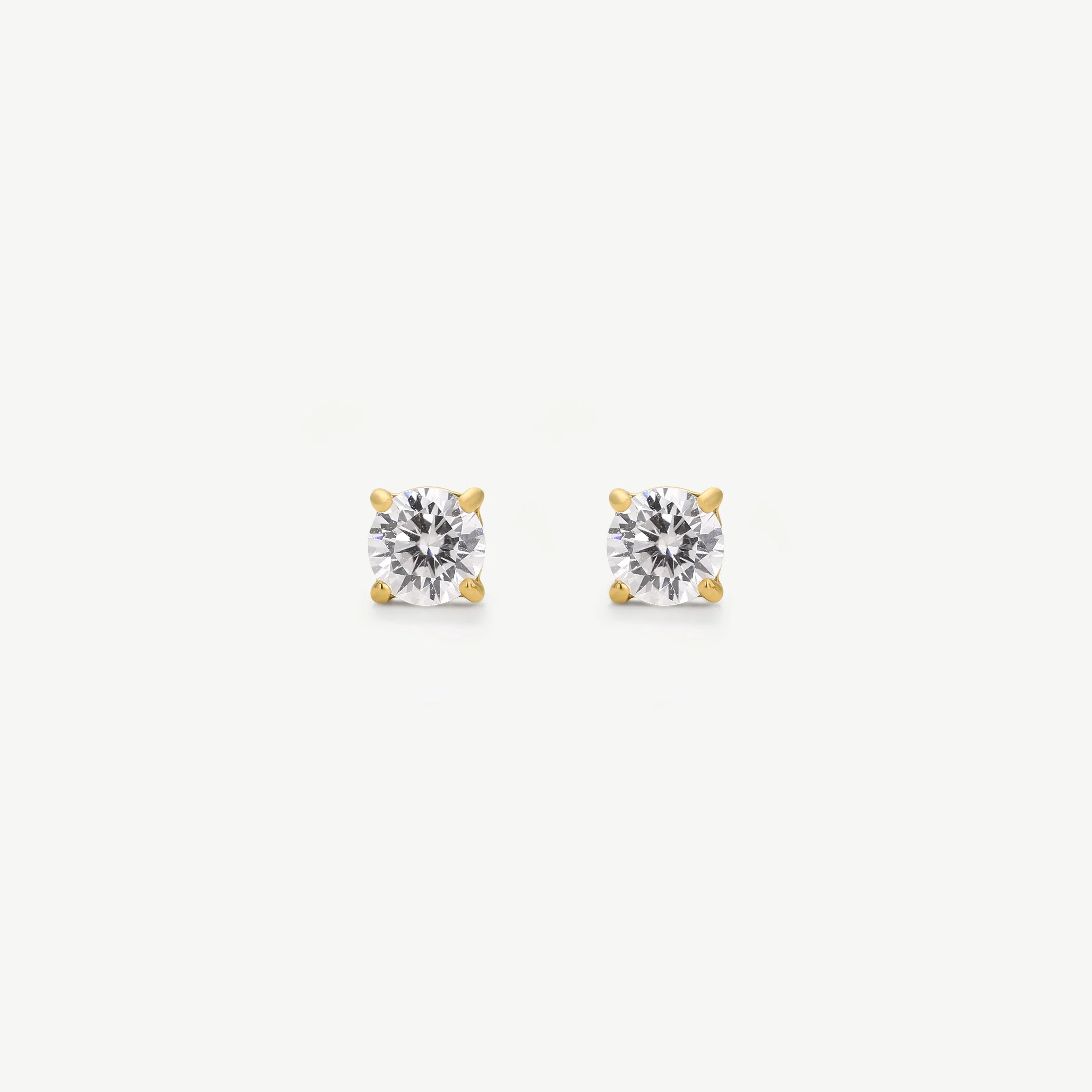 Pair of round diamond stud earrings in four-prong yellow gold settings on white background