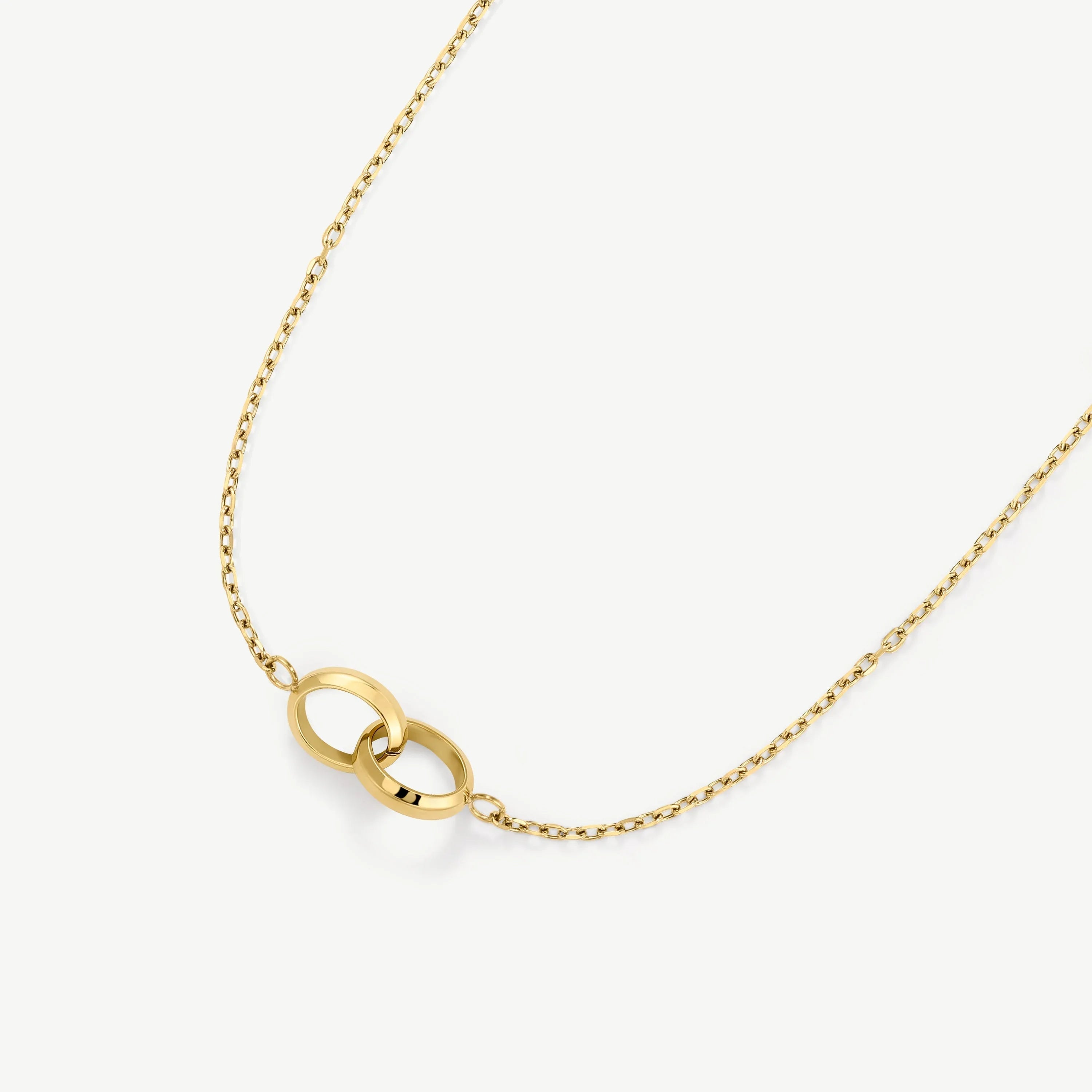 Gold necklace with two interlocking circular rings on a fine chain
