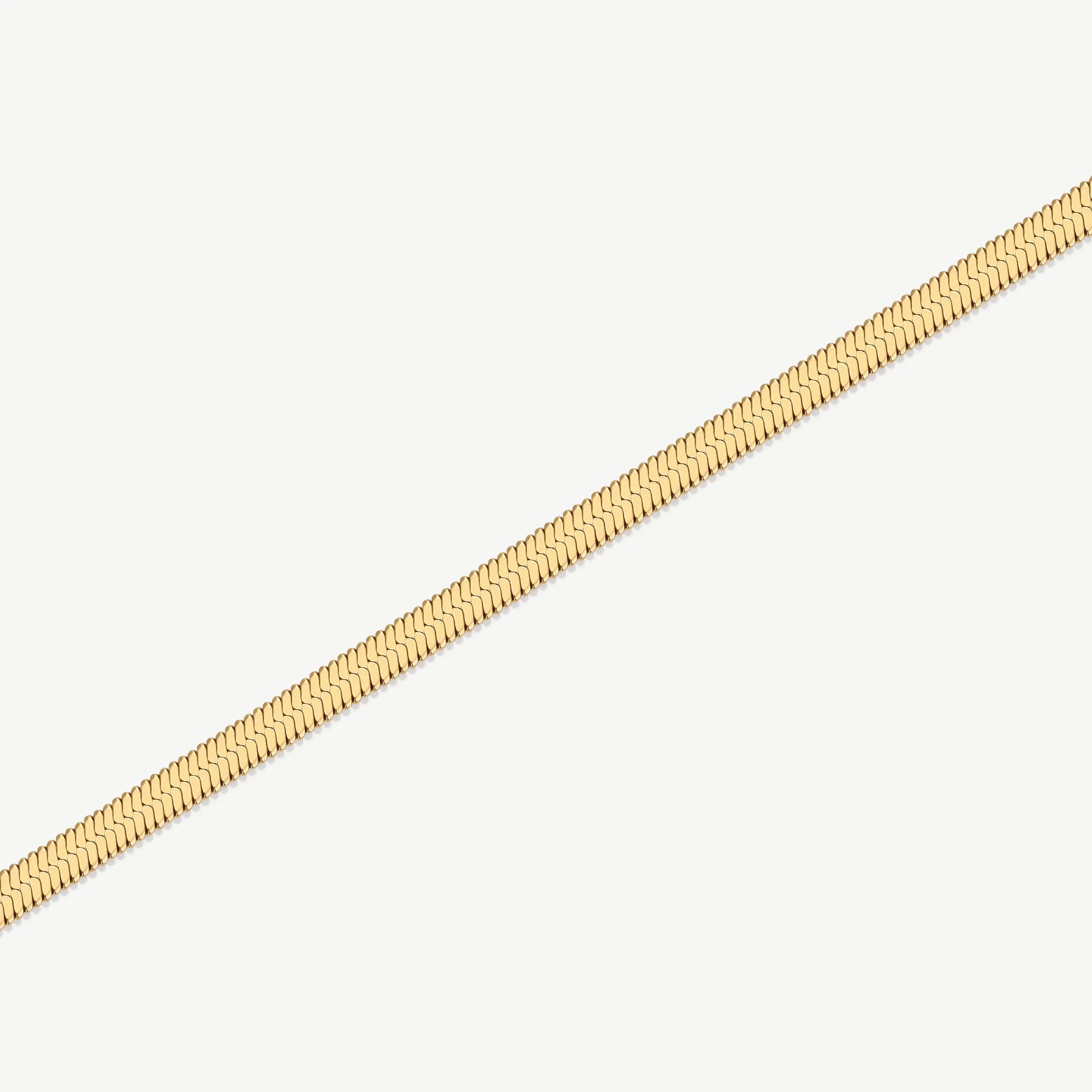 Close-up of a gold serpentine chain necklace on a white background